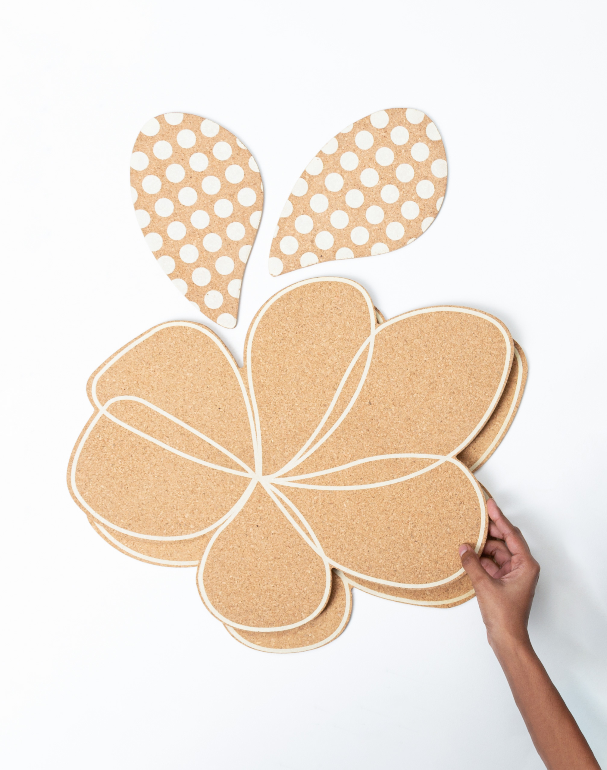 A person holding a floral shaped table mat.